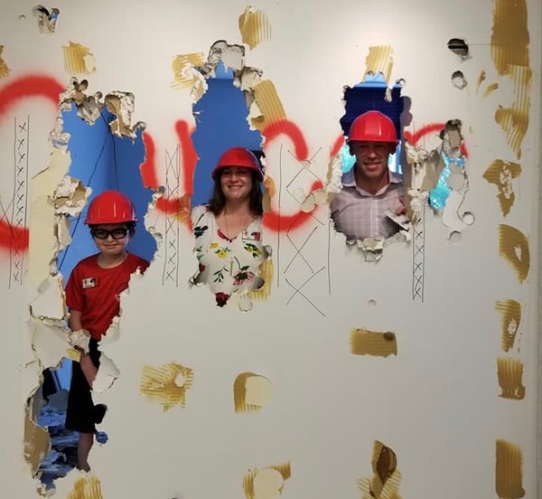 Lore Mangum and Family smashing through wall that spells cancer at Gilda's Club Kentuckiana