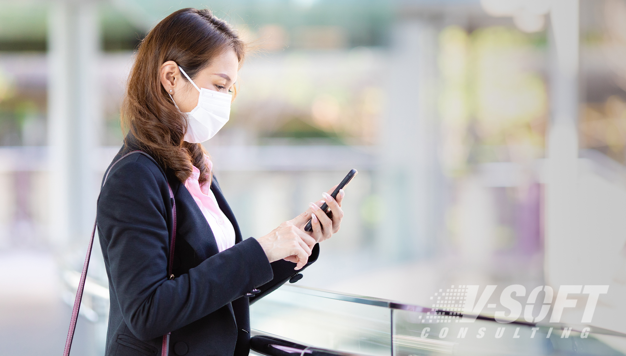 Woman with mask takes self-certification survey via mobile device upon entering the workplace
